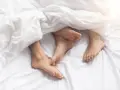Stopy pary pod białym przykryciem, blisko siebie, jakby szukając komfortu, nawet jeśli punkt G jest gdzie indziej.