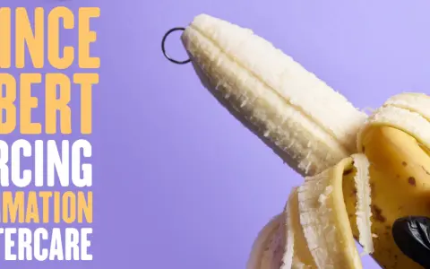 Banan z kółkiem, symbolizującym kolczyk w chuju, na fioletowym tle. Tekst: "PRINCE ALBERT PIERCING INFORMATION & AFTERCARE".