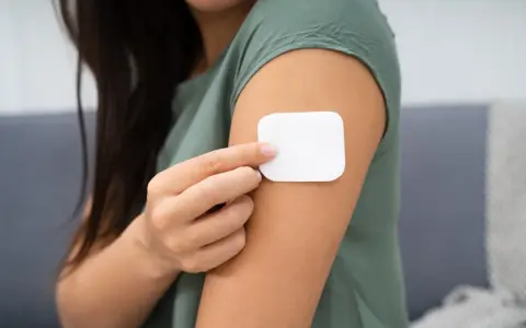Kobieta przykleja plaster antykoncepcyjny. Przed użyciem warto zapoznać się z przeciwwskazaniami.