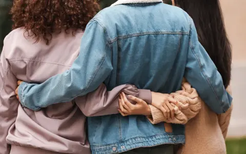 Trzy osoby obejmują się. Ich bliskość symbolizuje wsparcie i przyjaźń, nawet jeśli tworzą związek bez mieszkania razem.